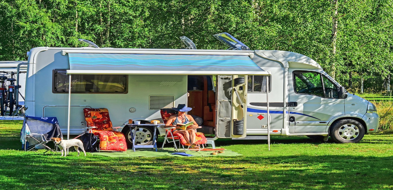 RV with woman reading book outside