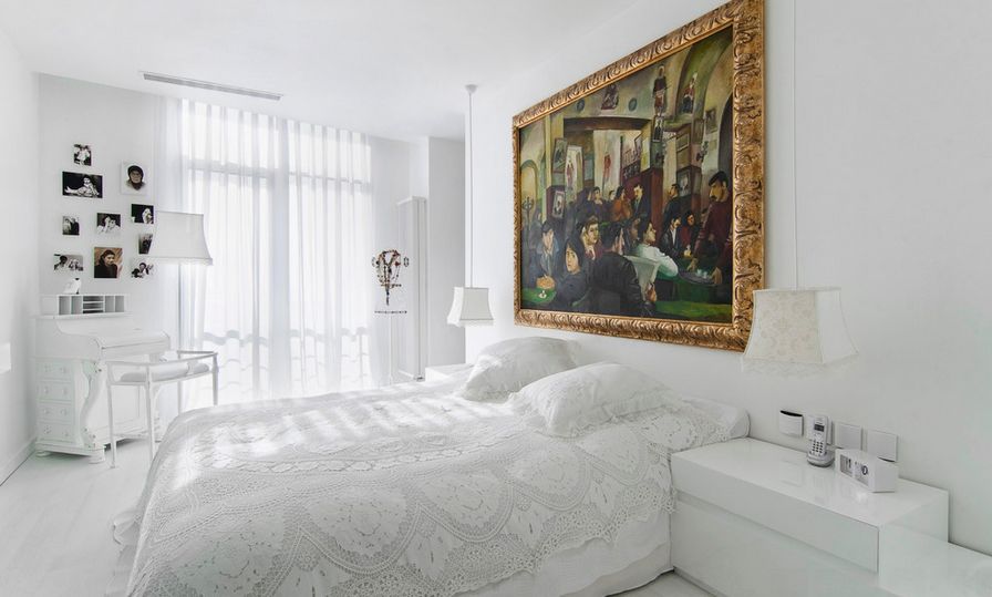 White bedroom with gold framed art above the bed