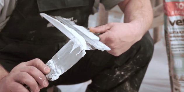 Как выровнять стены шпаклёвкой: маленьким шпателем наберите немного шпаклёвки и нанесите её на край широкого шпателя