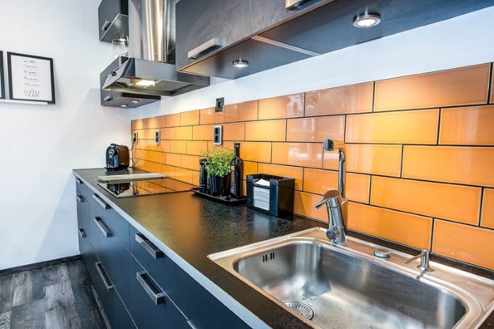 Оранжевая плитка на фартуке линейной кухни
