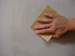 photo sanding joint compound by hand with a sheet of sandpaper