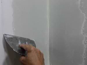photo smoothing joint compound edges on an inside drywall corner