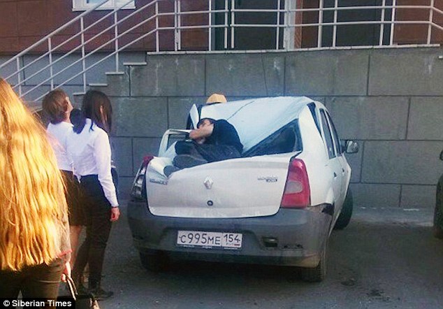 Alexander Shadrin is pictured on the buckled roof of the Romanian-made Renault Logan that 