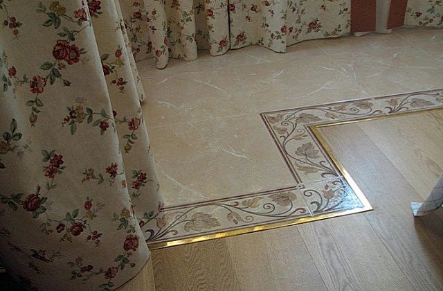 Металлический молдинг разделяет области керамической плитки и ламината на полу