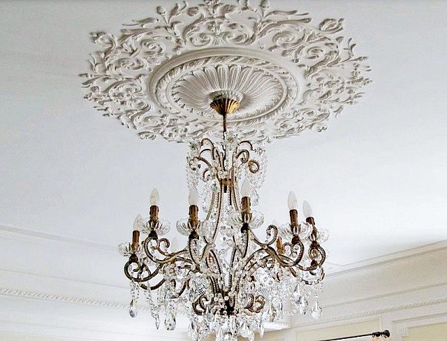 В стиле «барокко», помимо линейных молдингов, обязательно напрашивается декоративная розетка под люстру, строго по центру потолочной поверхности