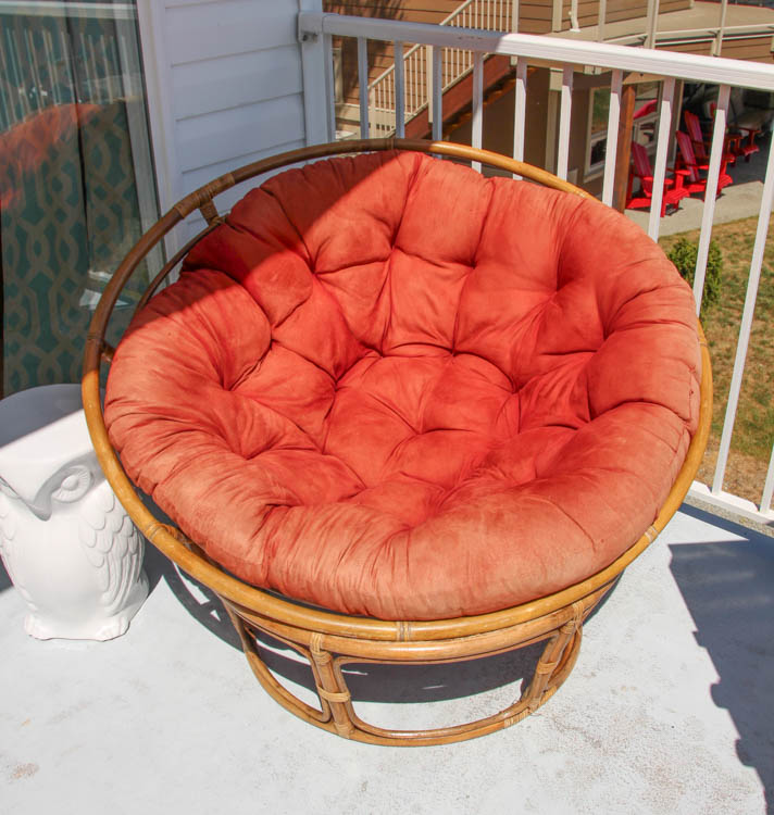 An old red papasan cushion on a chair on the porch.