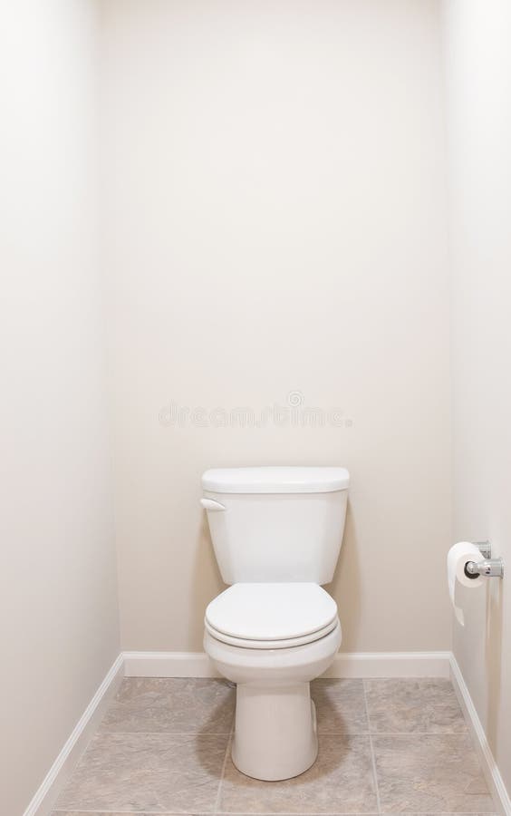 American White Toilet with Tan Tiled Floor. Minimalist American white toilet with tan tiled floor royalty free stock photos