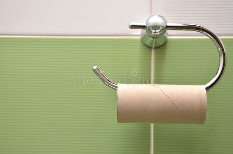 Empty roll on toilet paper holder with white and green tiles in background. Close view royalty free stock photography
