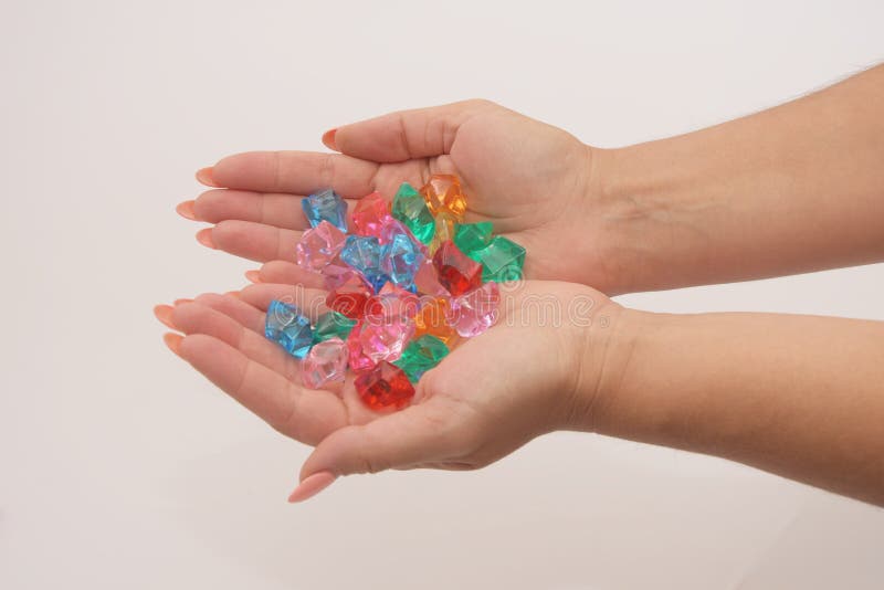 Female hands clasped hold multi-colored glass pebbles on a light background.  Jewelry and toys for women and children. stock photo