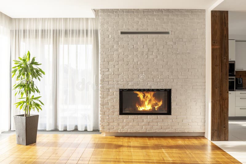 Fireplace on brick wall in bright living room interior of house. With plant and windows. Real photo royalty free stock image