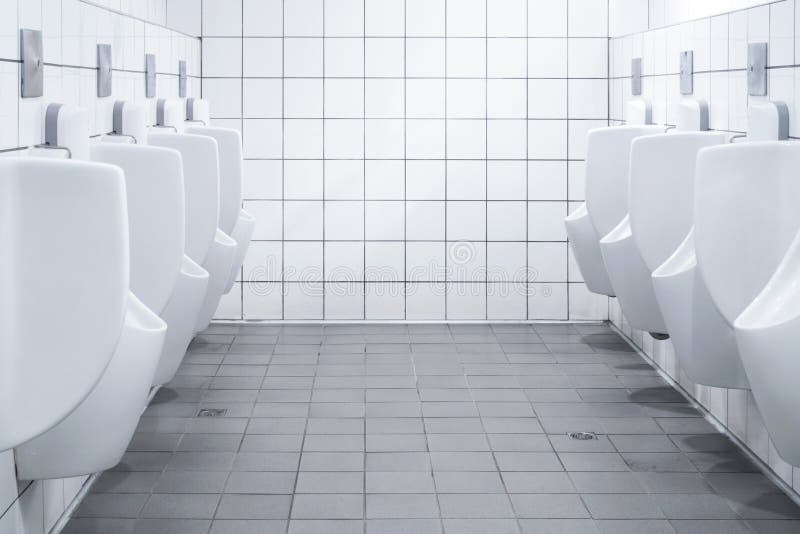Row of white urinals in men public bathroom toilet with white tiles wall.  stock image