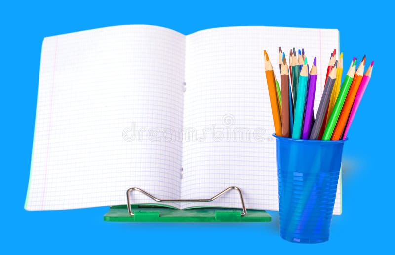 School notebook and colored pencils in a blue glass on a white background. royalty free stock images