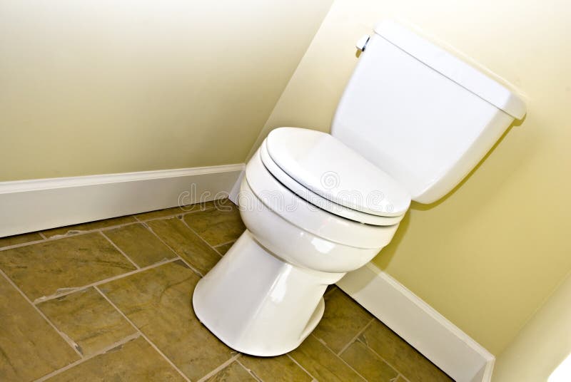 Toilet and Tile Floor. Toilet against a yellow wall on a tile floor royalty free stock photography