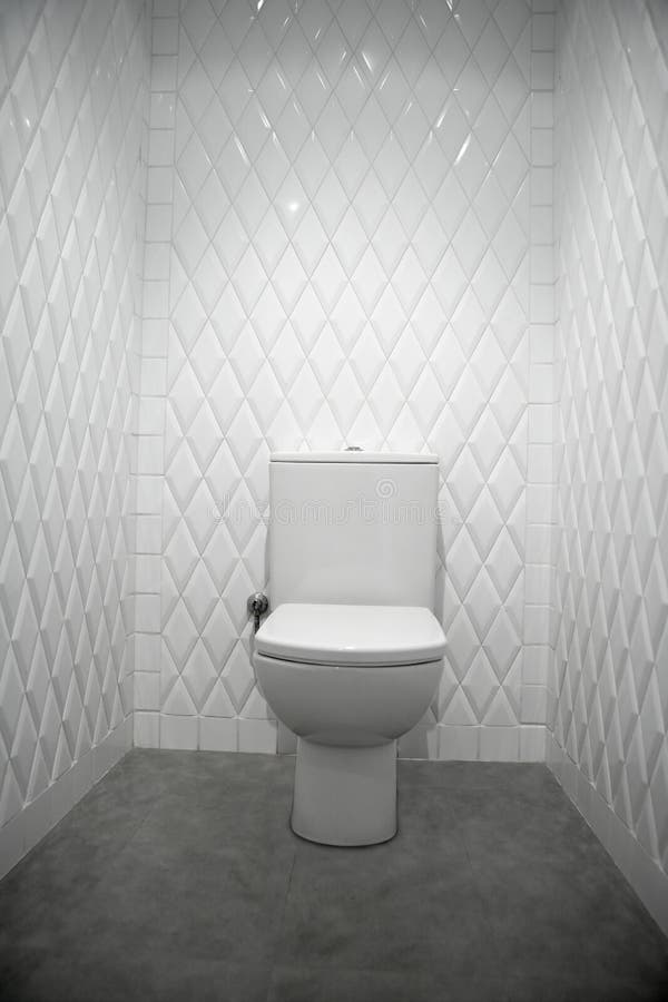 Toilet in a white room diamond shape tiles. Toilet in a white narrow room diamond shape tiles stock images