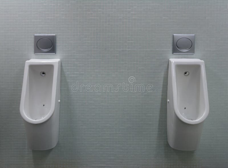 Urinals with two white painted a fly on the toilet. In the tiled wall royalty free stock images