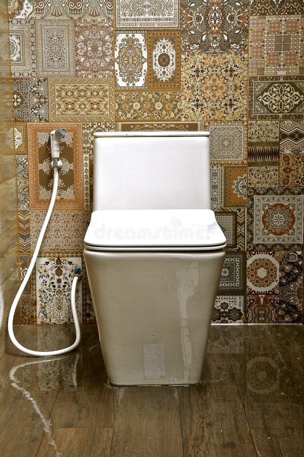 White ceramic toilet in a tiled room. White ceramic toilet in an ornately tiled public rest room stock images