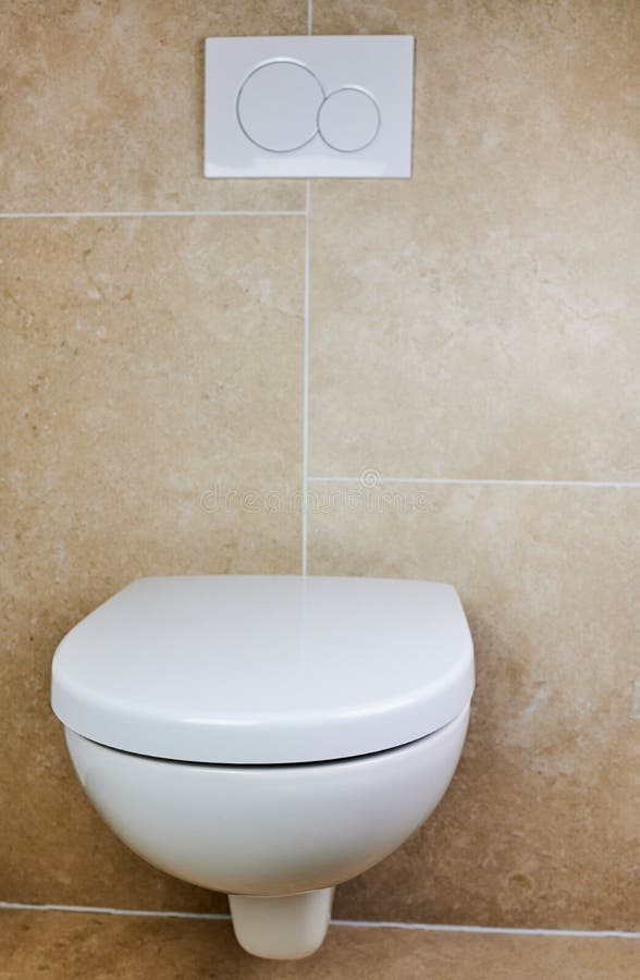 White toilet against brown tiles. Wall-mounted white toilet against brown tiles in a private bathroom stock photography