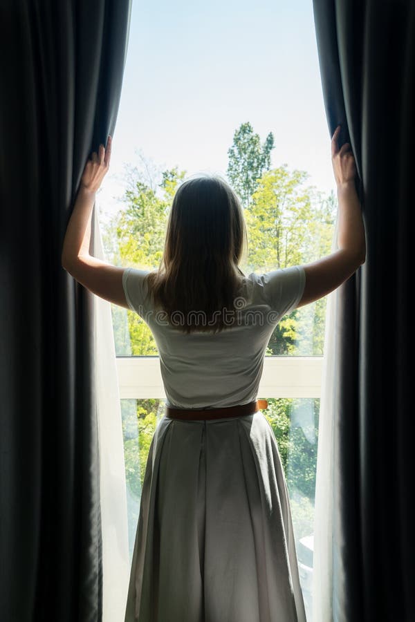 Woman opening curtains stock photo