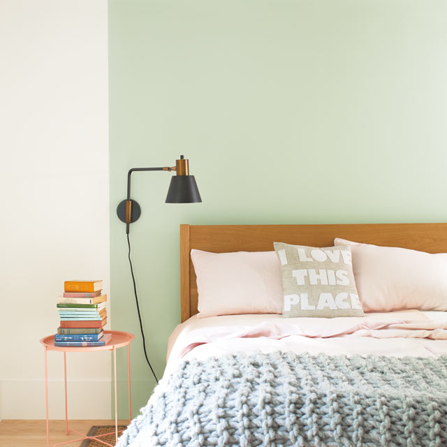 A bed set against a light green feature wall